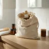 Leinensack auf dem Badezimmerregal mit Kosmetik- und Pflegeaccessoires in hellem Interieur