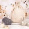 Leinensack mit Kordelzug auf dekorativem Hintergrund mit Kürbissen und Wolle im Herbststil